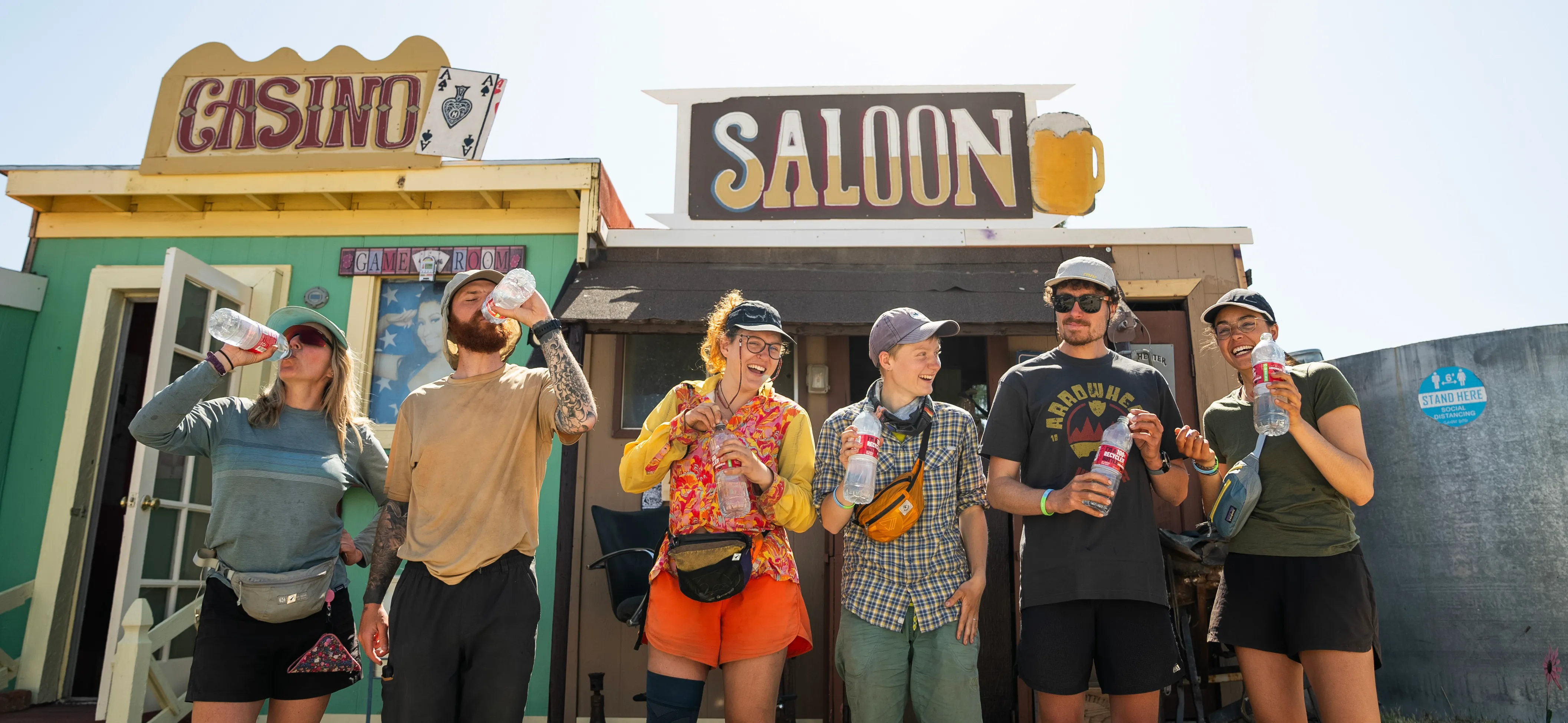 Small rustic city hall building with pillars, a clock tower, and 'City Hall' sign in a rural area with dry grass and hills.