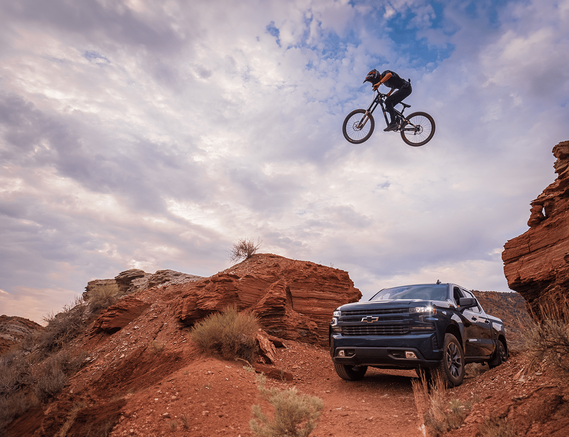 mountain biker launching across rocks and over a car