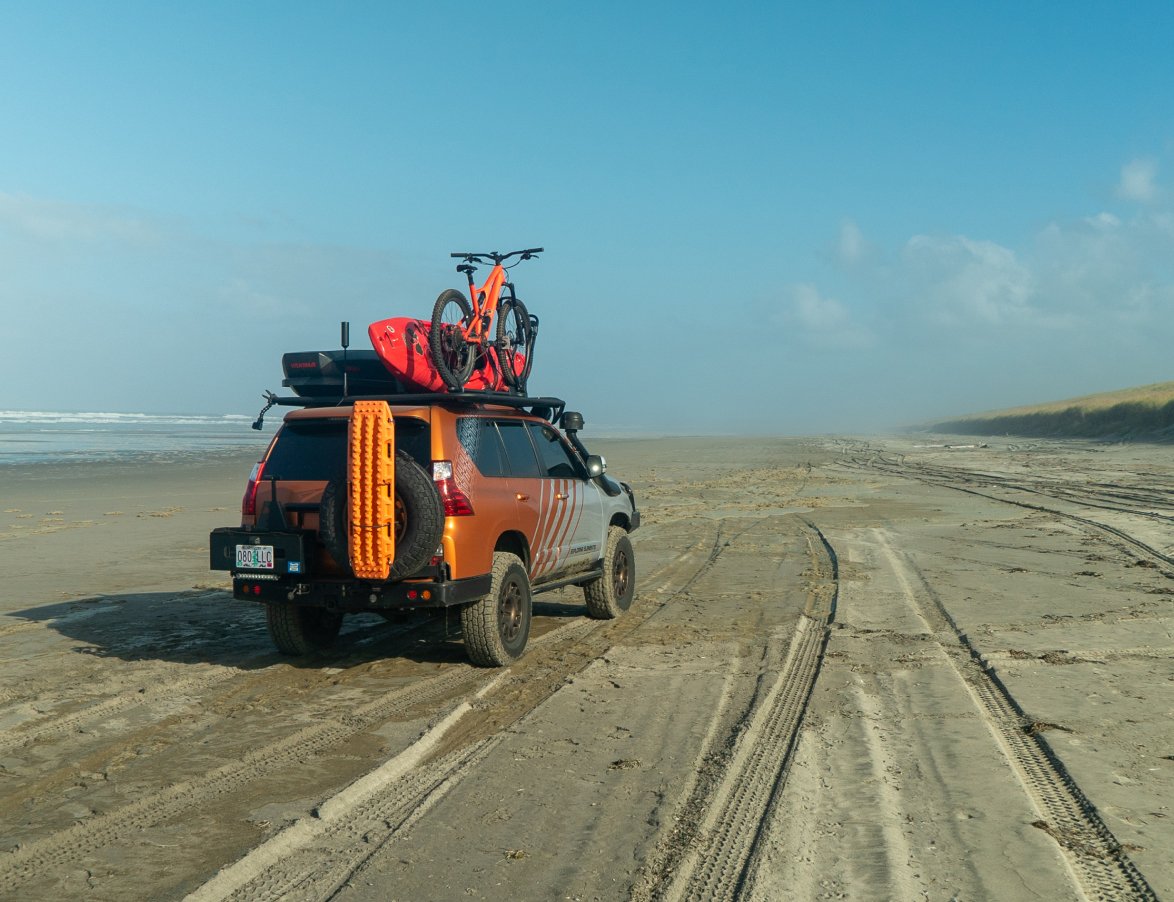 truck loaded with surfing gear riding over a beack